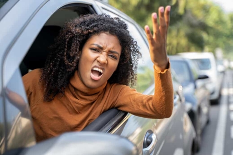Young woman hangs out the window in traffic because she is upset with road rage
