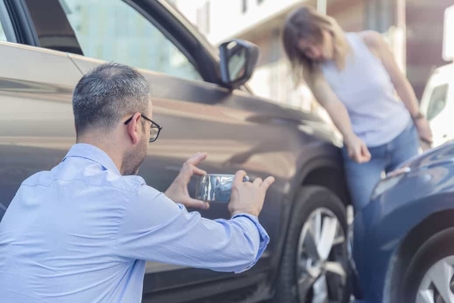 Man takes a photo of the damage after getting into a car accident